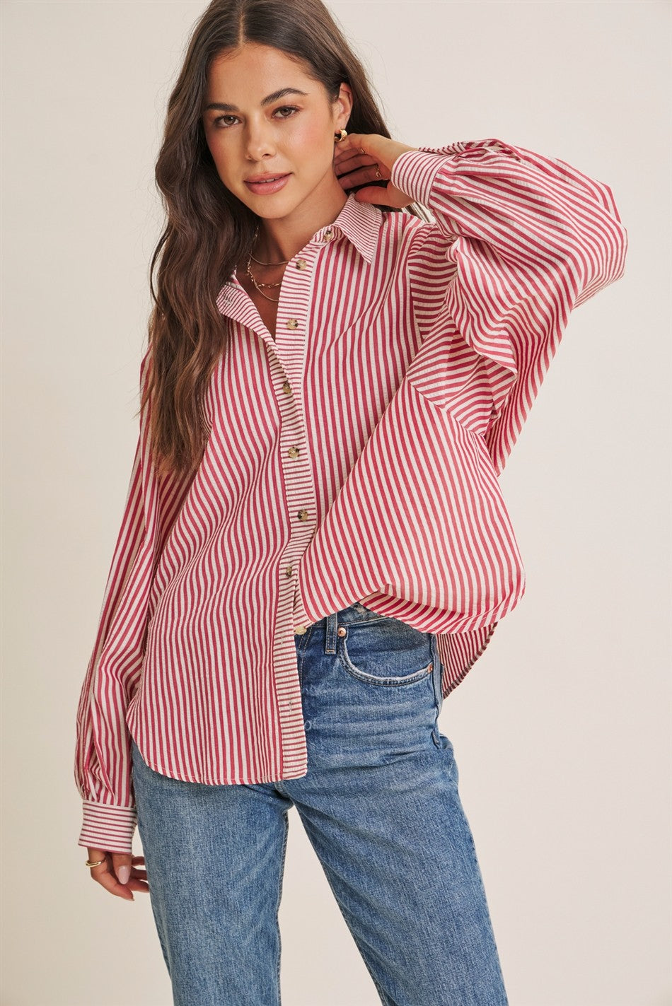 woman wearing a red and white striped oversized button-up shirt with balloon sleeves and blue jeans