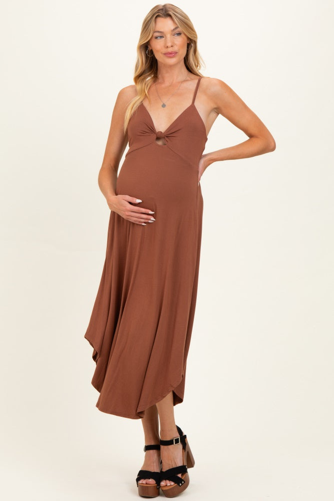 woman wearing a brown maternity maxi dress with a knotted front detail and holding her baby bump