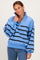 woman wearing a light blue oversized pullover with black stripes and snap-button collar paired with blue jeans