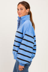 woman wearing a light blue oversized sweatshirt with black horizontal stripes and snap buttons on the collar