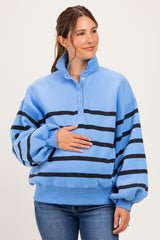 woman wearing a blue striped maternity sweatshirt with a quarter-zip and holding her baby bump