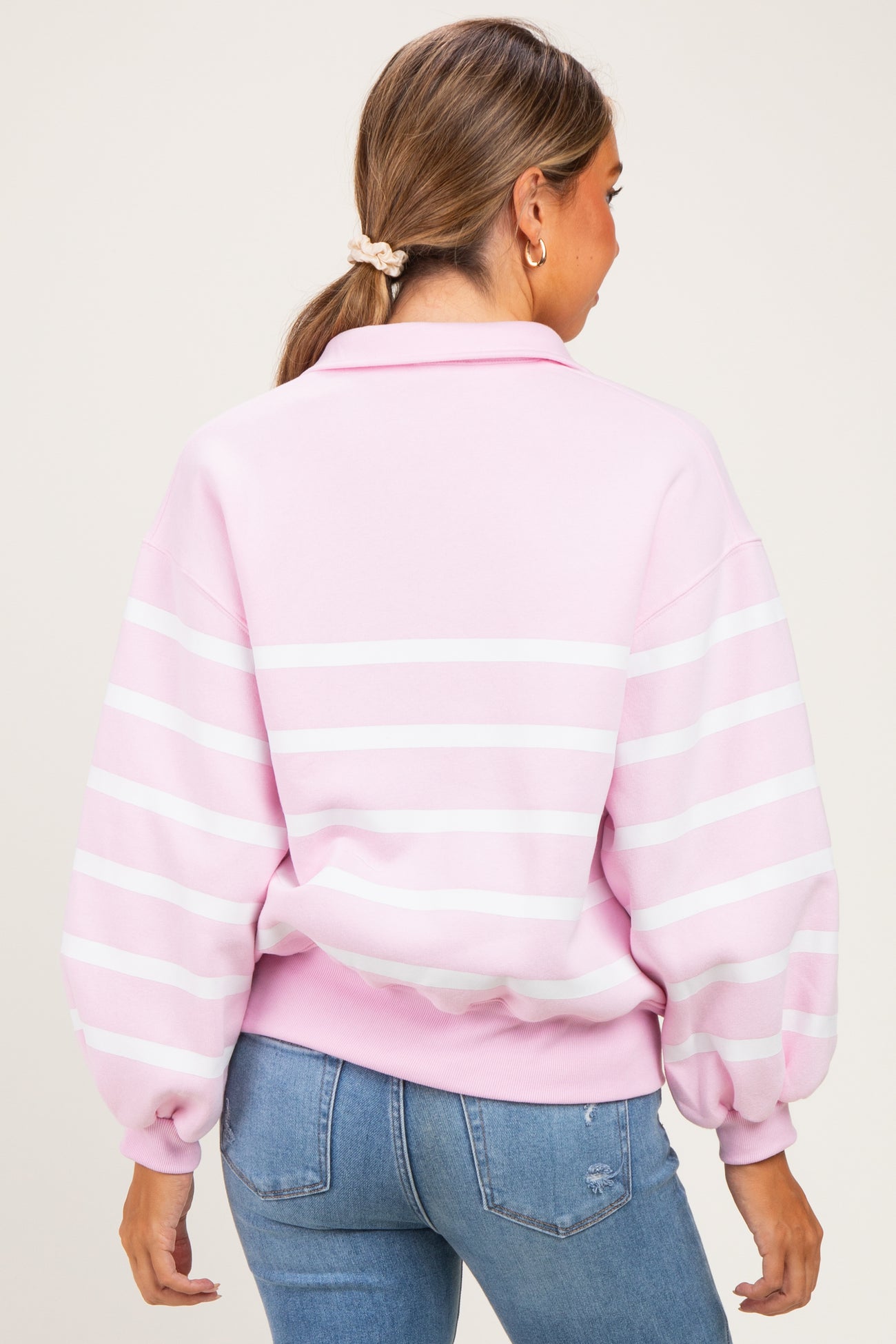 woman wearing a light pink striped maternity sweatshirt, styled with a relaxed fit and balloon sleeves