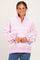 woman wearing a pink striped pullover sweatshirt with a half-button placket and oversized sleeves