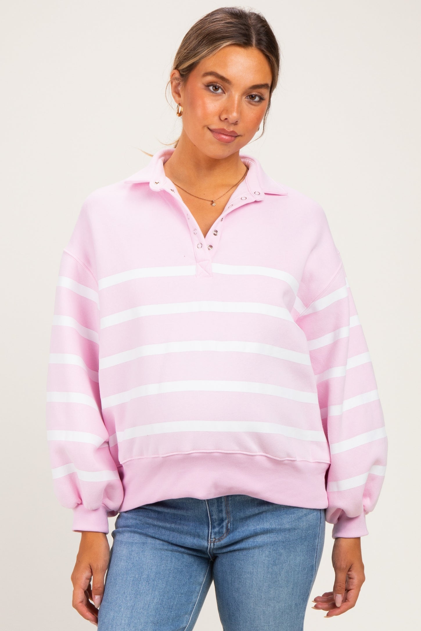 woman wearing a pink striped maternity pullover with a collar and button details