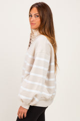 woman wearing a beige striped oversized sweatshirt with button detailing on the collar and black leggings