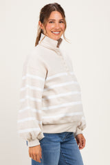 woman wearing a cream striped maternity pullover with a high collar and button details, displaying her baby bump