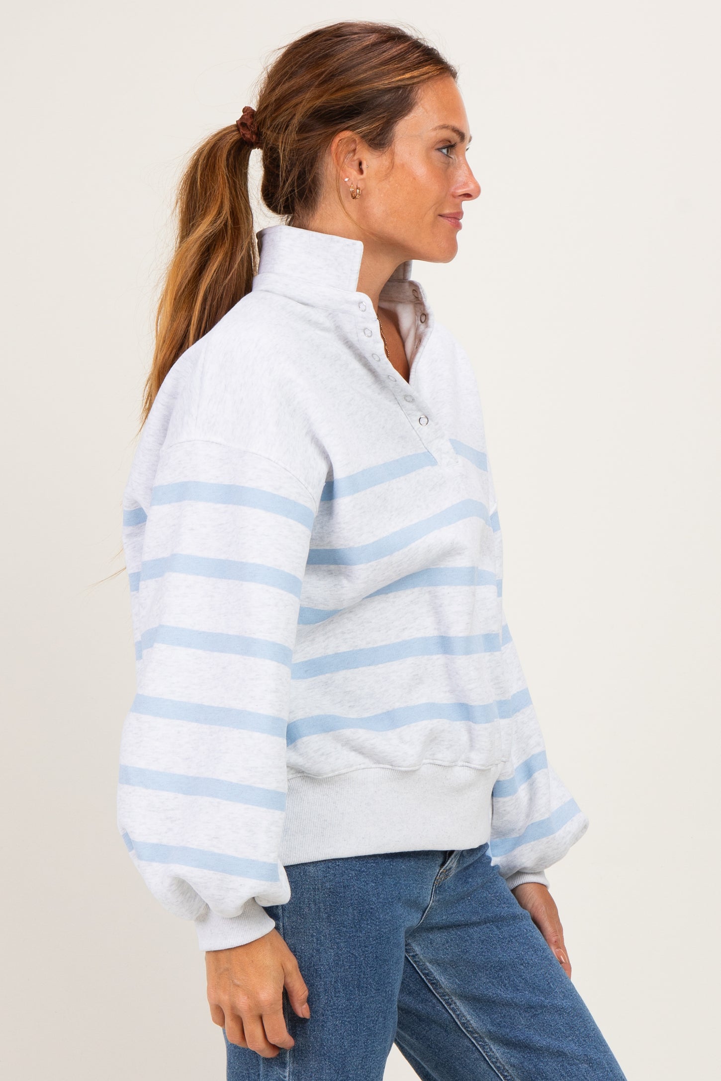 woman wearing a light gray and blue striped pullover sweatshirt with a high collar and balloon sleeves