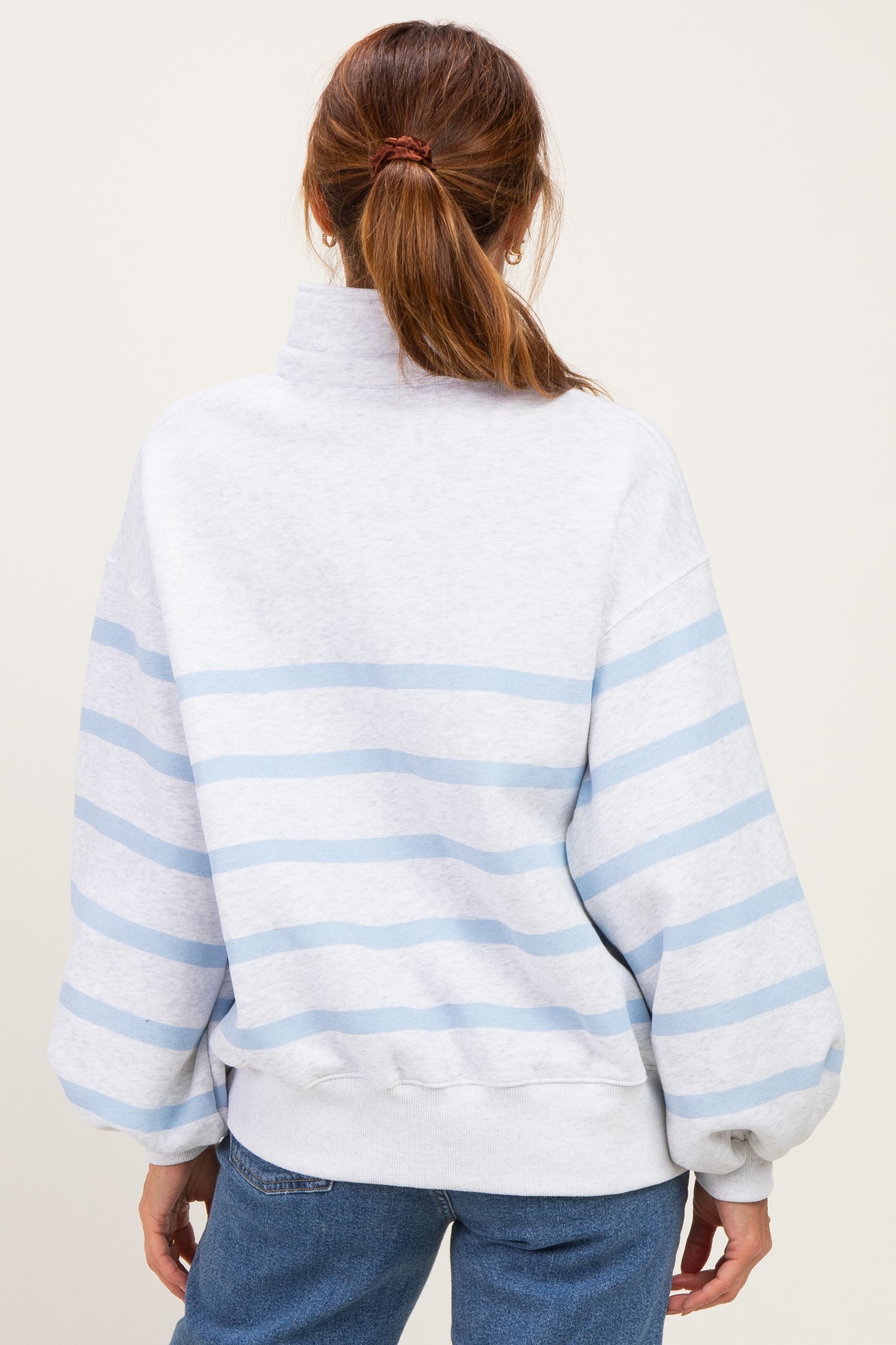 woman wearing a gray and light blue striped oversized sweatshirt with a high neck and balloon sleeves