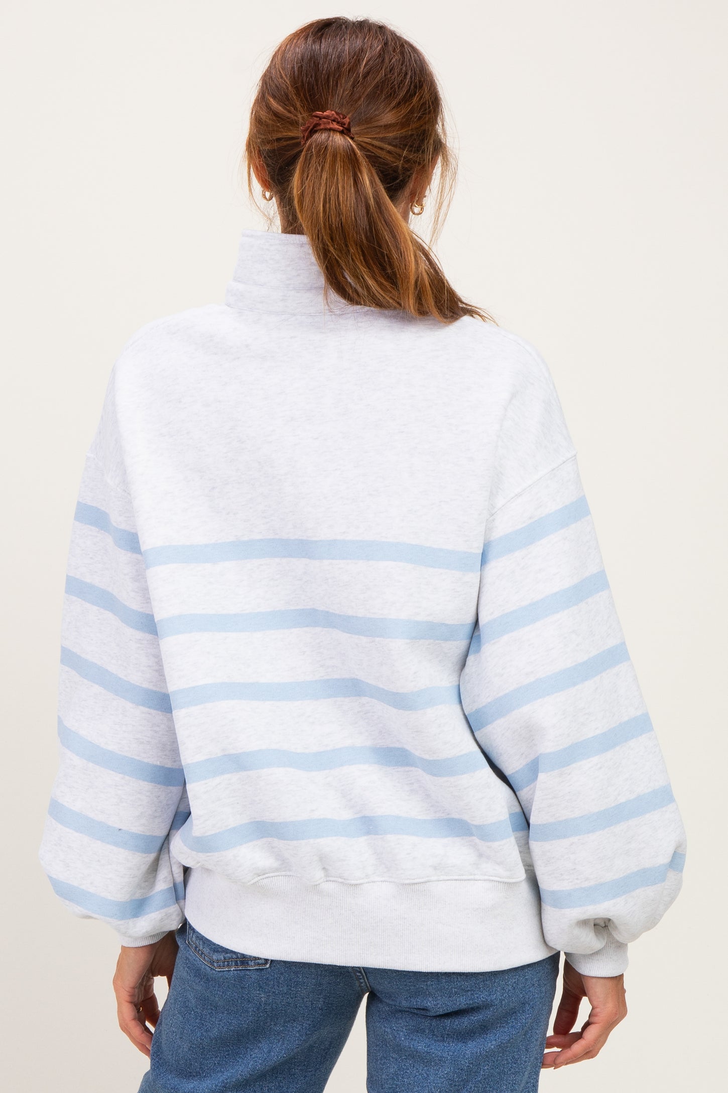 woman wearing a gray and light blue striped oversized sweatshirt with a high neck and balloon sleeves