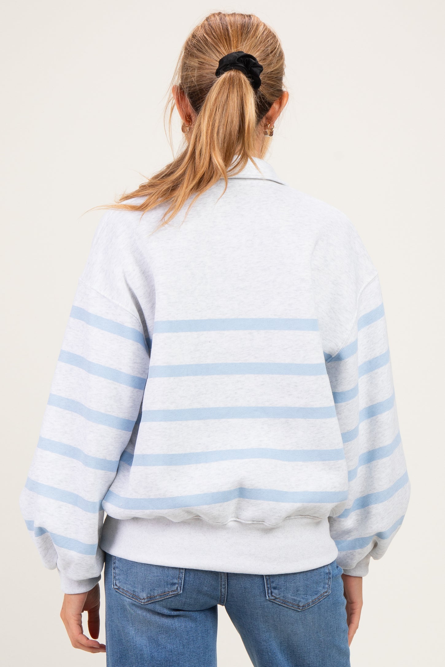 woman wearing a gray and light blue striped maternity sweatshirt with a relaxed fit and balloon sleeves