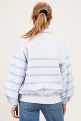 woman wearing a gray and light blue striped maternity sweatshirt with a relaxed fit and balloon sleeves