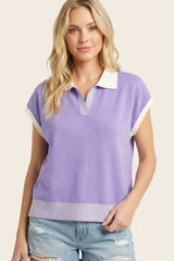 woman wearing a lilac short sleeve polo sweater with a white collar and striped hem, paired with distressed denim shorts
