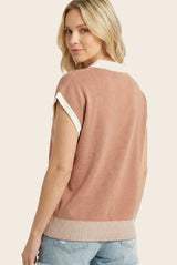 woman wearing a pink short sleeve sweater with white collar and ribbed hem, styled with light blue jeans