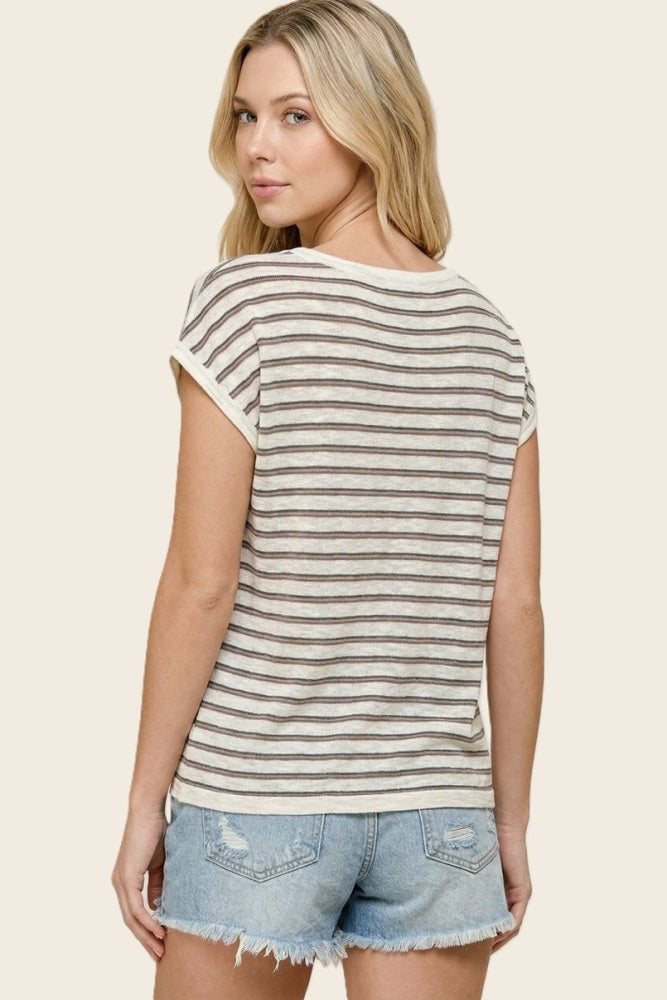 woman wearing a cream and brown striped short sleeve top with rolled sleeves and denim cut-off shorts