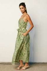 woman wearing a green and cream striped maxi dress with a tie waist and pockets, standing against a light background
