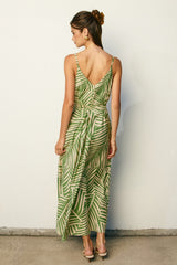 woman wearing a green palm leaf print maxi dress with a back tie detail and spaghetti straps