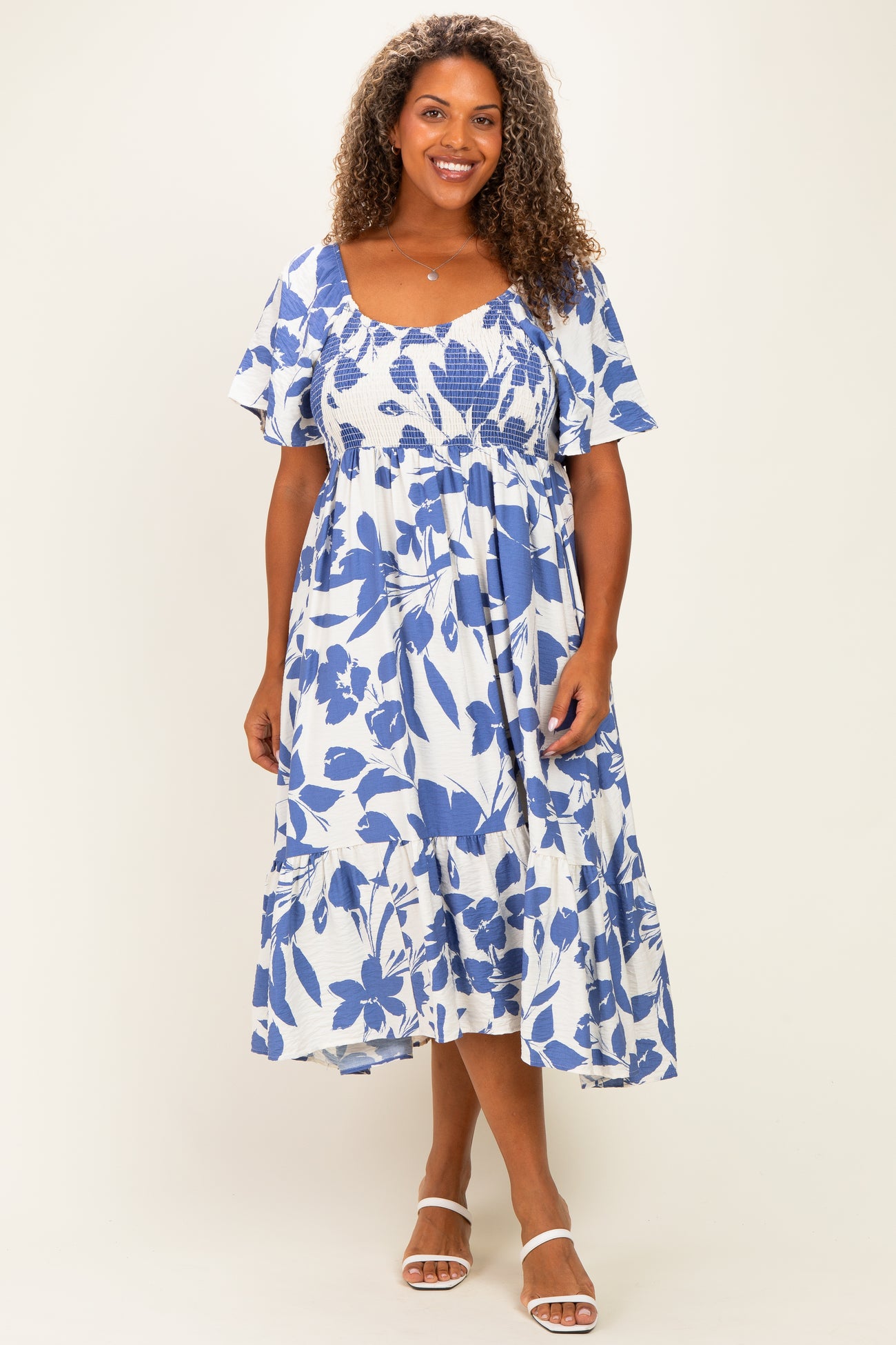 woman wearing a blue and white floral plus-size midi dress with short flutter sleeves and a tiered skirt