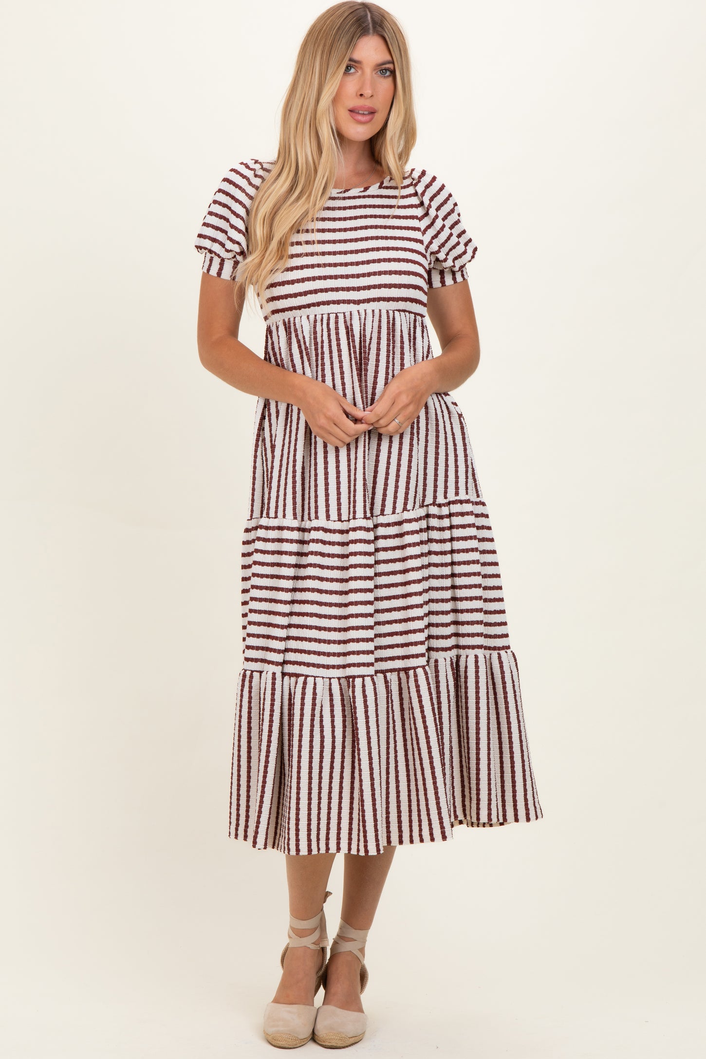 woman wearing a striped tiered midi dress with short puff sleeves and a flared hemline