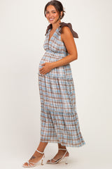 woman wearing a brown and blue checked maternity maxi dress with tie straps and a visible baby bump