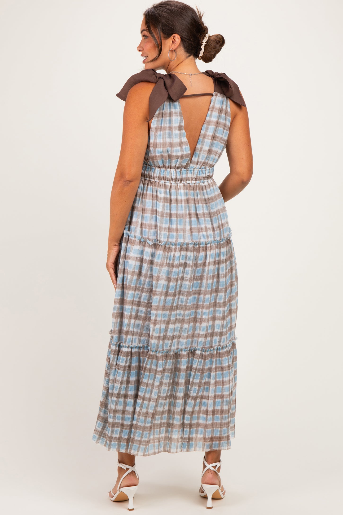 woman wearing a maternity maxi dress with a checkered pattern and tie straps, showing the back view