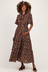 woman wearing a brown floral maternity maxi dress with short sleeves and a gathered waist, holding her baby bump