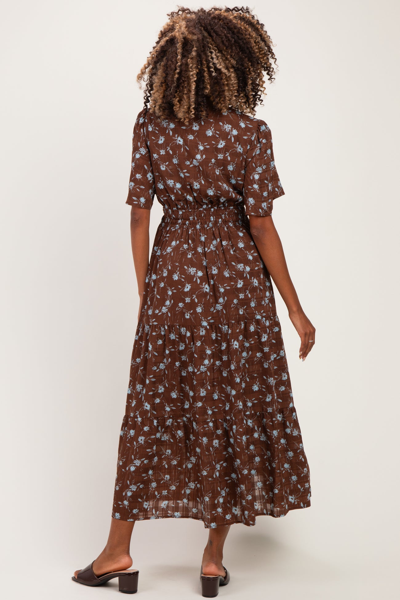 woman wearing a brown floral maternity dress with short sleeves and a cinched waist, seen from the back