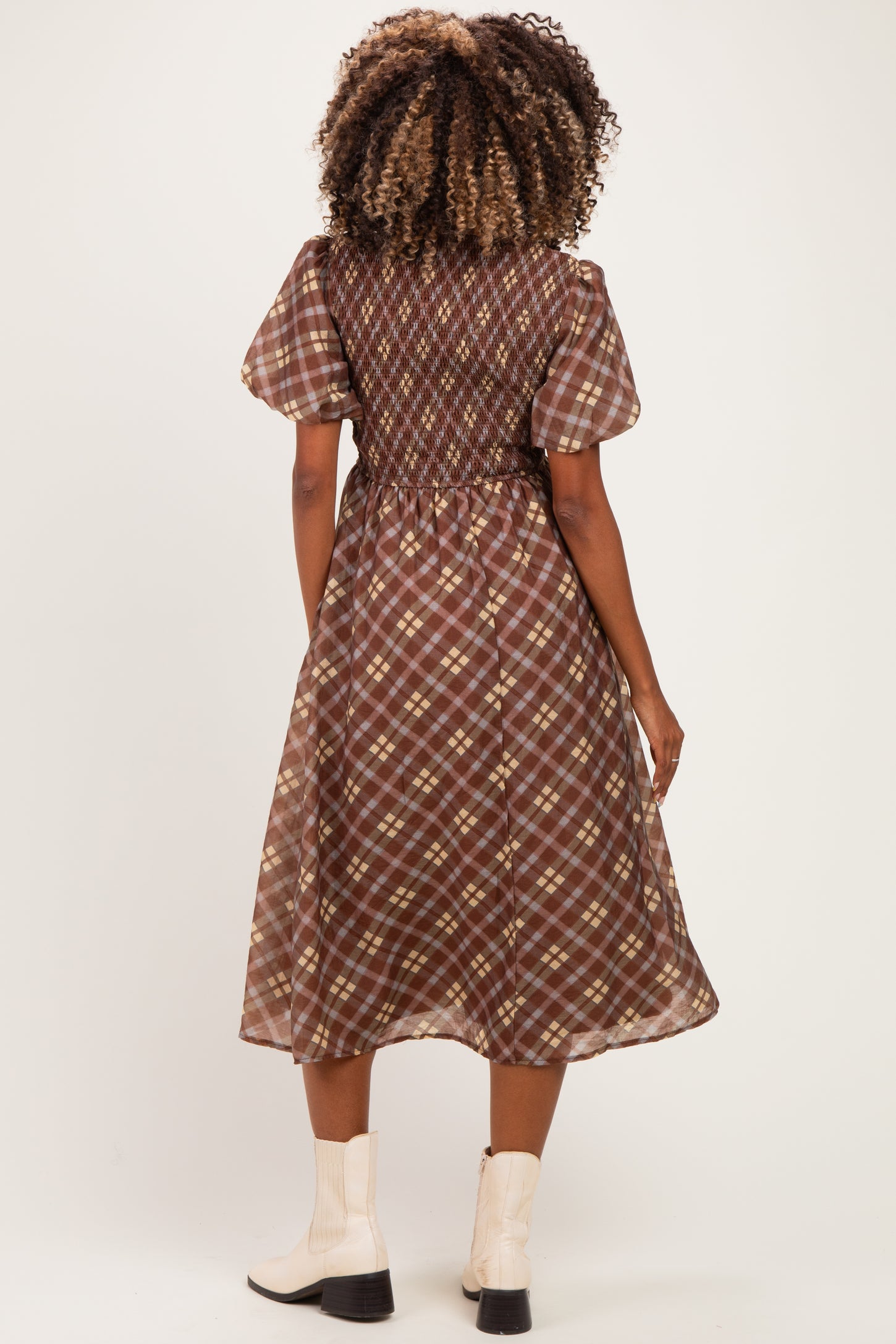 woman wearing a brown plaid maternity dress with puff sleeves and a cinched waist, showcasing a flowing skirt