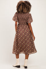 woman wearing a brown plaid maternity dress with puff sleeves and a cinched waist, showcasing a flowing skirt