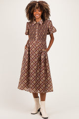 woman wearing a brown plaid maternity dress with short puff sleeves and pockets