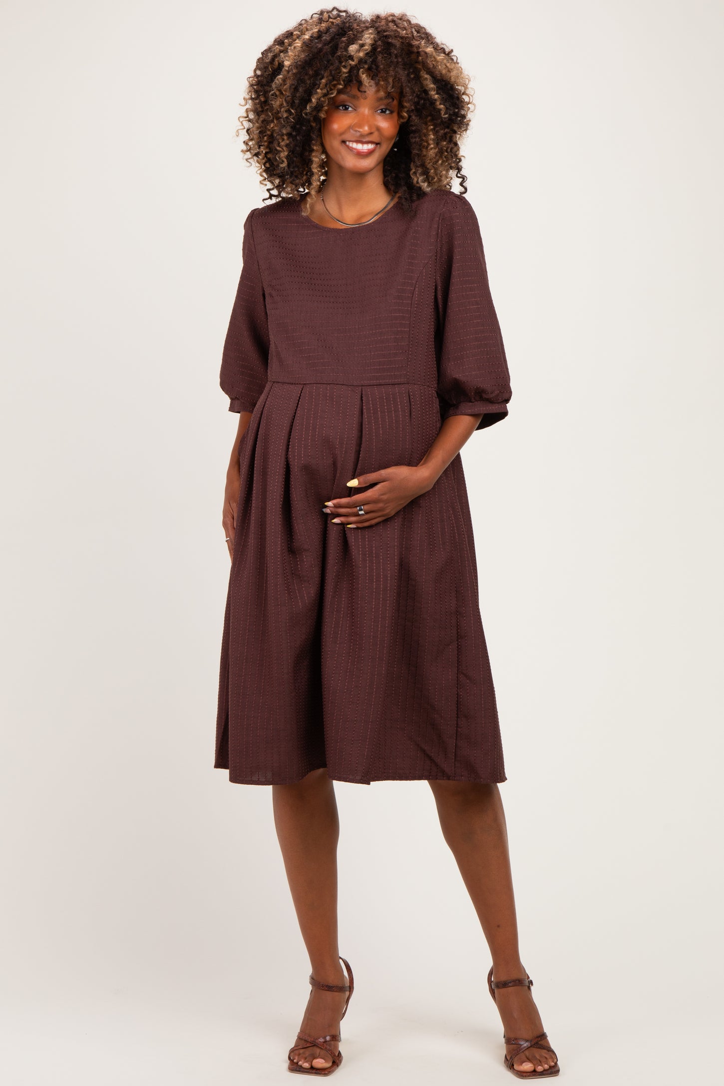 woman wearing a brown maternity dress with short puff sleeves and a baby bump visible