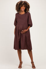 woman wearing a brown maternity dress with short puff sleeves and a baby bump visible