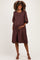 woman wearing a brown maternity dress with short puff sleeves and a baby bump visible