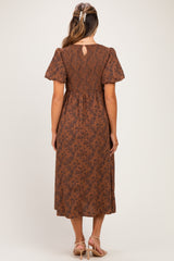 woman wearing a brown floral print maternity dress with puff sleeves and a keyhole back detail