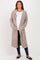 woman wearing a long beige cardigan with white trim and pockets over a white shirt and blue jeans