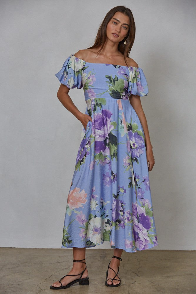 woman wearing a blue floral off-the-shoulder maxi dress with puff sleeves and pockets