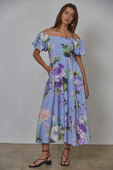 woman wearing a blue floral off-the-shoulder maxi dress with puff sleeves and pockets