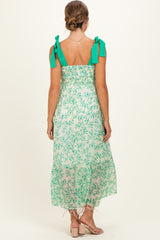 woman wearing a green floral maternity maxi dress with tie straps and a smocked back.