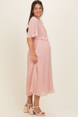 woman wearing a pink pleated maternity dress with short sleeves and a visible baby bump
