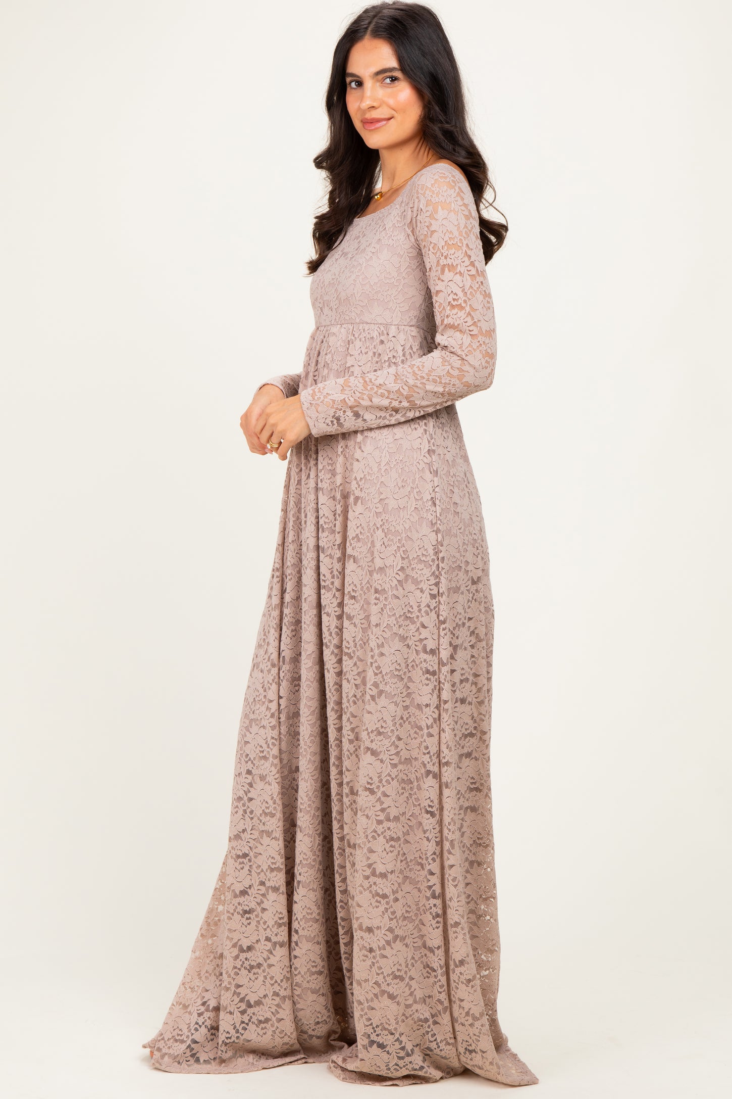 woman wearing a long sleeve beige lace maxi dress standing sideways with a relaxed fit