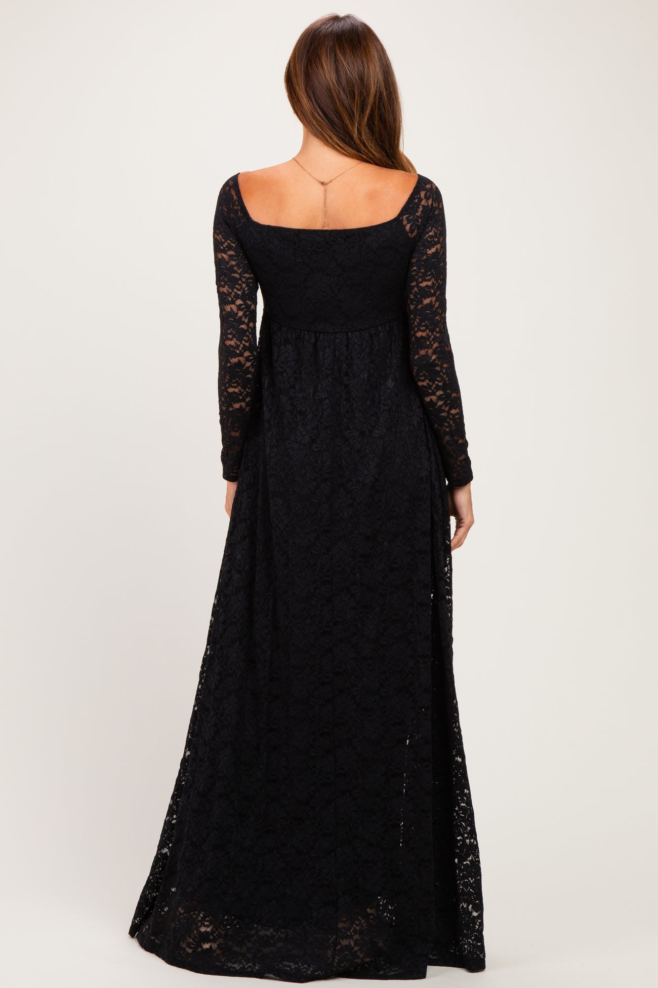 woman wearing a black long sleeve lace maxi dress, showing the back view and a flowy silhouette