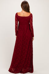 woman wearing a burgundy long sleeve lace maxi dress, showing the back view with a fitted bodice and flowing skirt