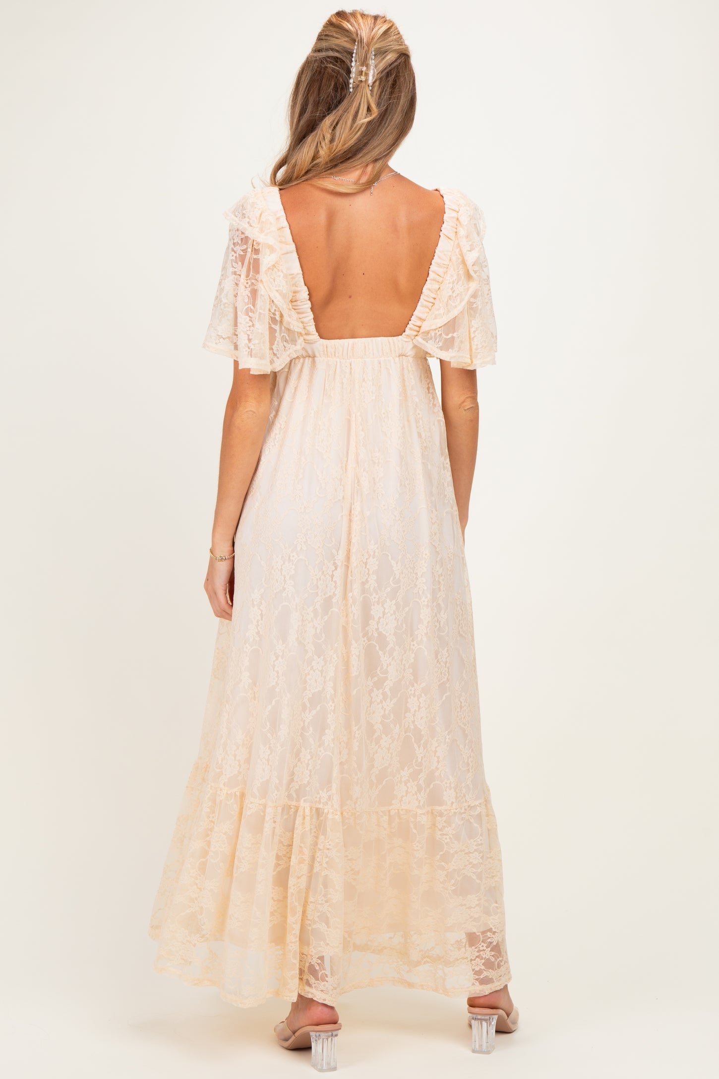 woman wearing a cream lace maternity maxi dress with flutter sleeves and a scoop back