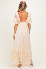 woman wearing a cream lace maternity maxi dress with flutter sleeves and a scoop back