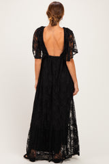 woman wearing a black lace maxi dress with short flutter sleeves and a deep back cutout