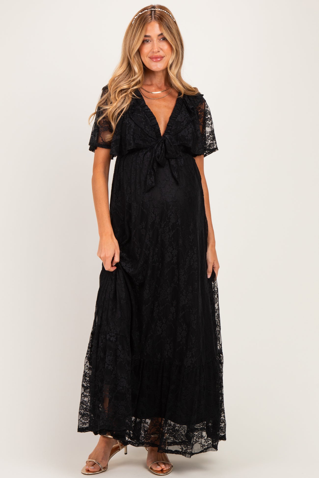woman wearing a black lace maxi maternity dress with a tie front and short sleeves, showing her baby bump