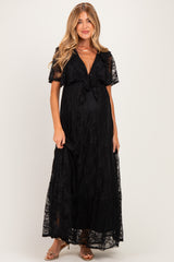 woman wearing a black lace maxi maternity dress with a tie front and short sleeves, showing her baby bump