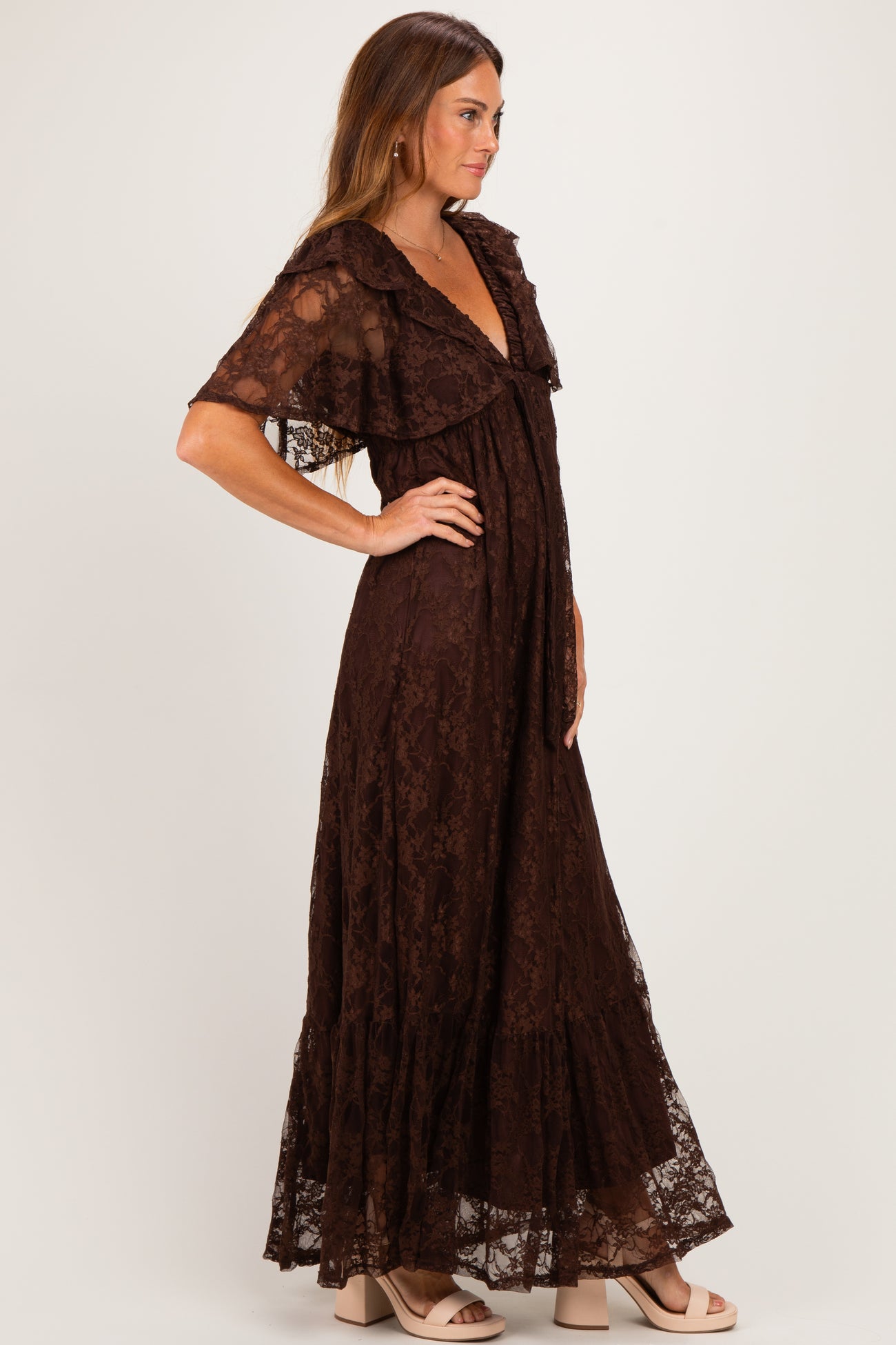 woman wearing a brown lace maxi dress with flutter sleeves and a plunging neckline