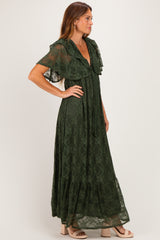 woman wearing a forest green lace maxi dress with flutter sleeves and a tiered skirt, standing in profile