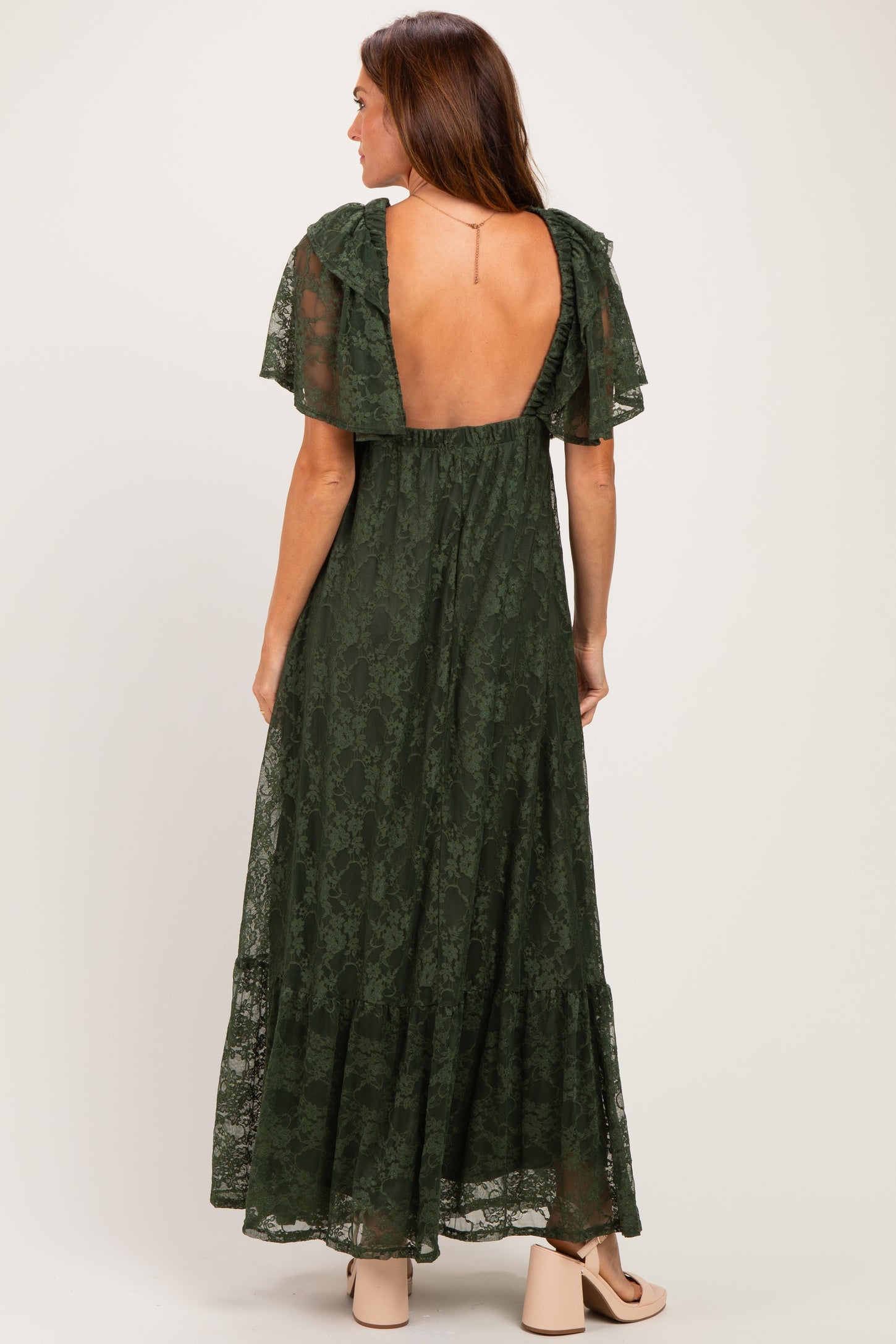 woman wearing a dark green lace maxi dress with flutter sleeves and a low back design