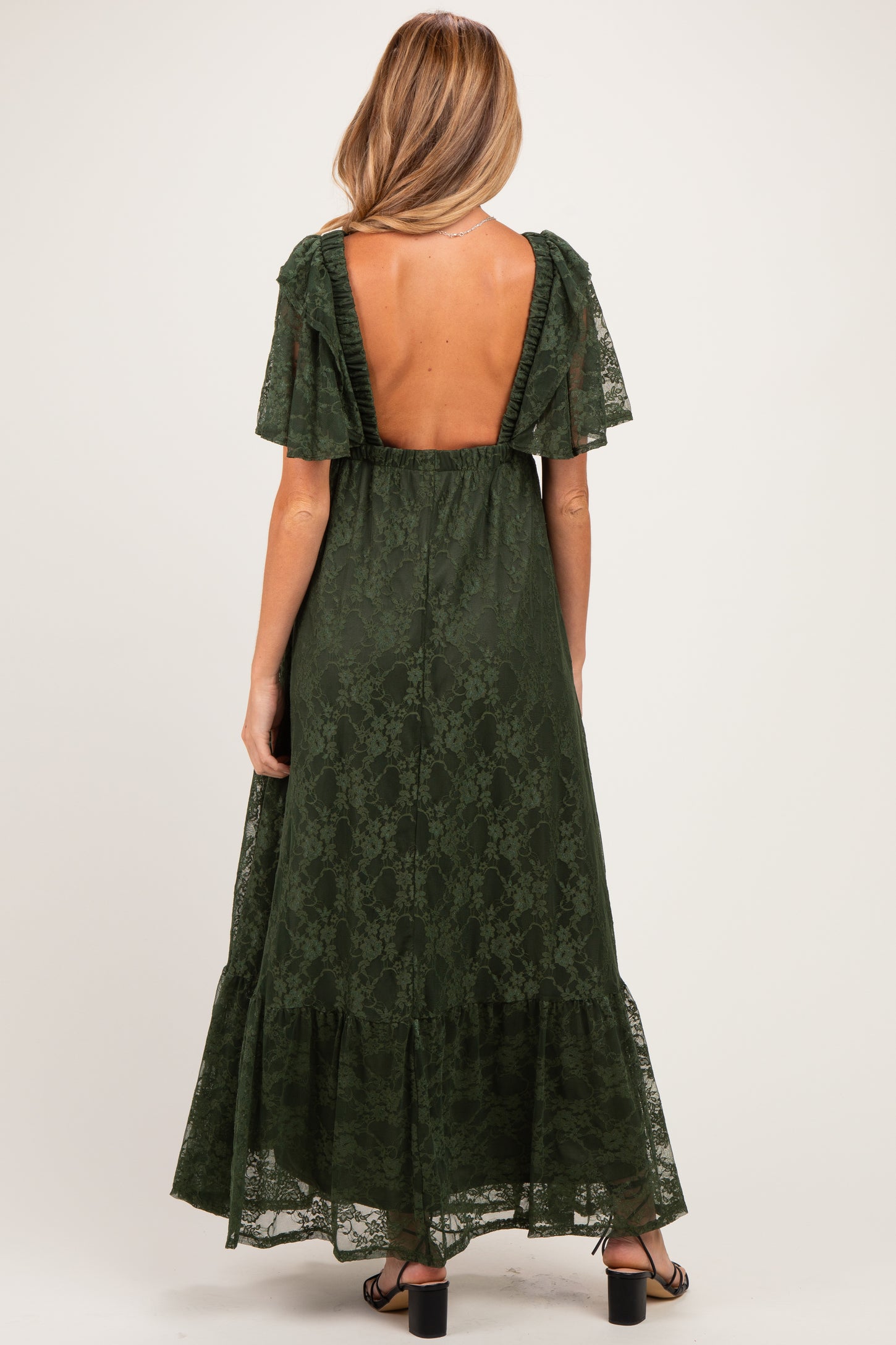 woman wearing a dark green lace maternity maxi dress with a low back and ruffle sleeves